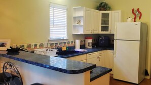 Cocina compacta con armarios blancos, lavavajillas integrado y refrigerador.