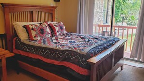 A bedroom with a wooden bed, a wooden nightstand, a chair, and a view of the outdoors through a balcony. - Private Room W/Deck**MiniFridge&Microwave (Kingsland)