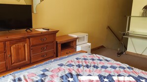 A bedroom with a wooden dresser, a flat-screen TV, a microwave, and a bed with a quilt. - Private Room W/Deck**MiniFridge&Microwave (Kingsland)