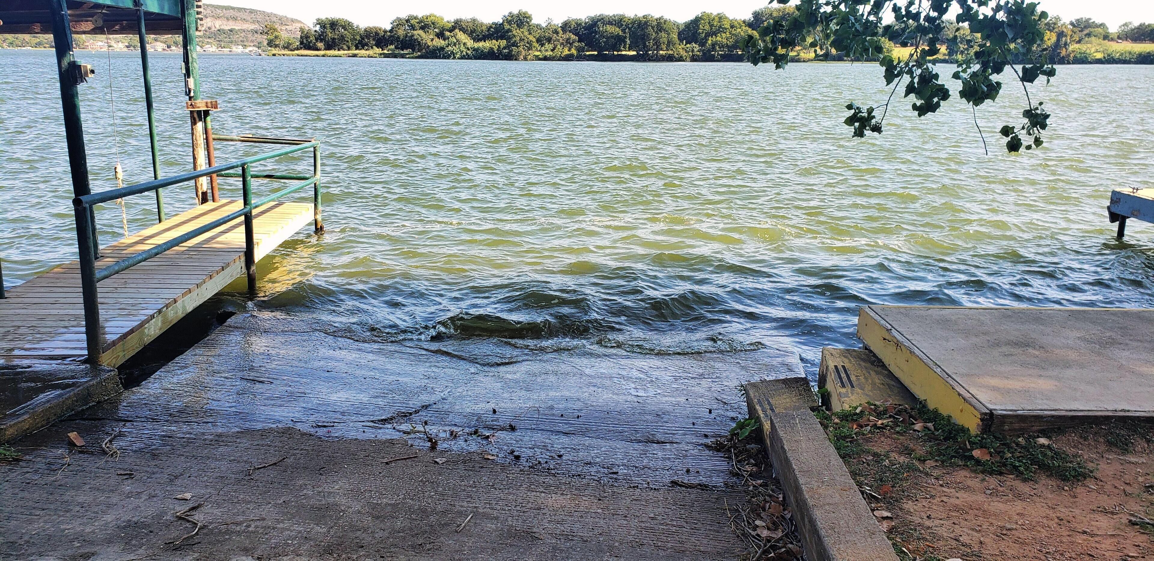 A wooden dock extending into a body of water with a concrete platform on the right.