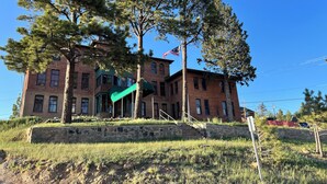 A historic building with a green awning, large windows, and an American flag. - Hotel St. Nicholas (Cripple Creek)