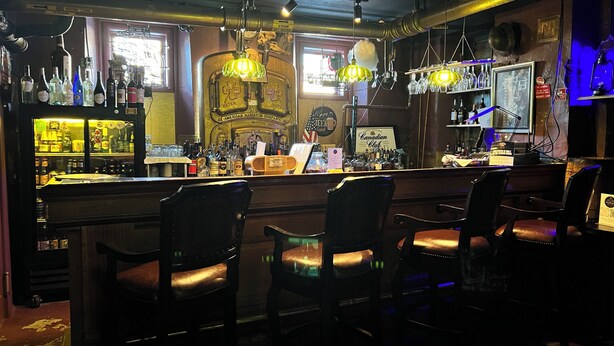 A bar with a vintage American radiator, shelves of liquor bottles, and leather chairs. - Hotel St. Nicholas (Cripple Creek)