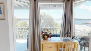 Enjoy a serene view of the water from this room's balcony, featuring a comfortable chair and a charming table with a vase of fresh flowers.