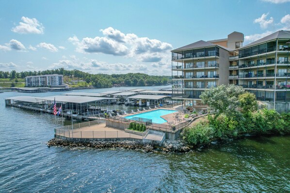 A waterfront hotel with a swimming pool, dock, and multiple balconies.