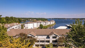A multi-story residential building with a view of a lake and a bridge in the background. - Regatta Bay 488 - Walk In 3 Bdrm Condo (Village of Four Seasons)