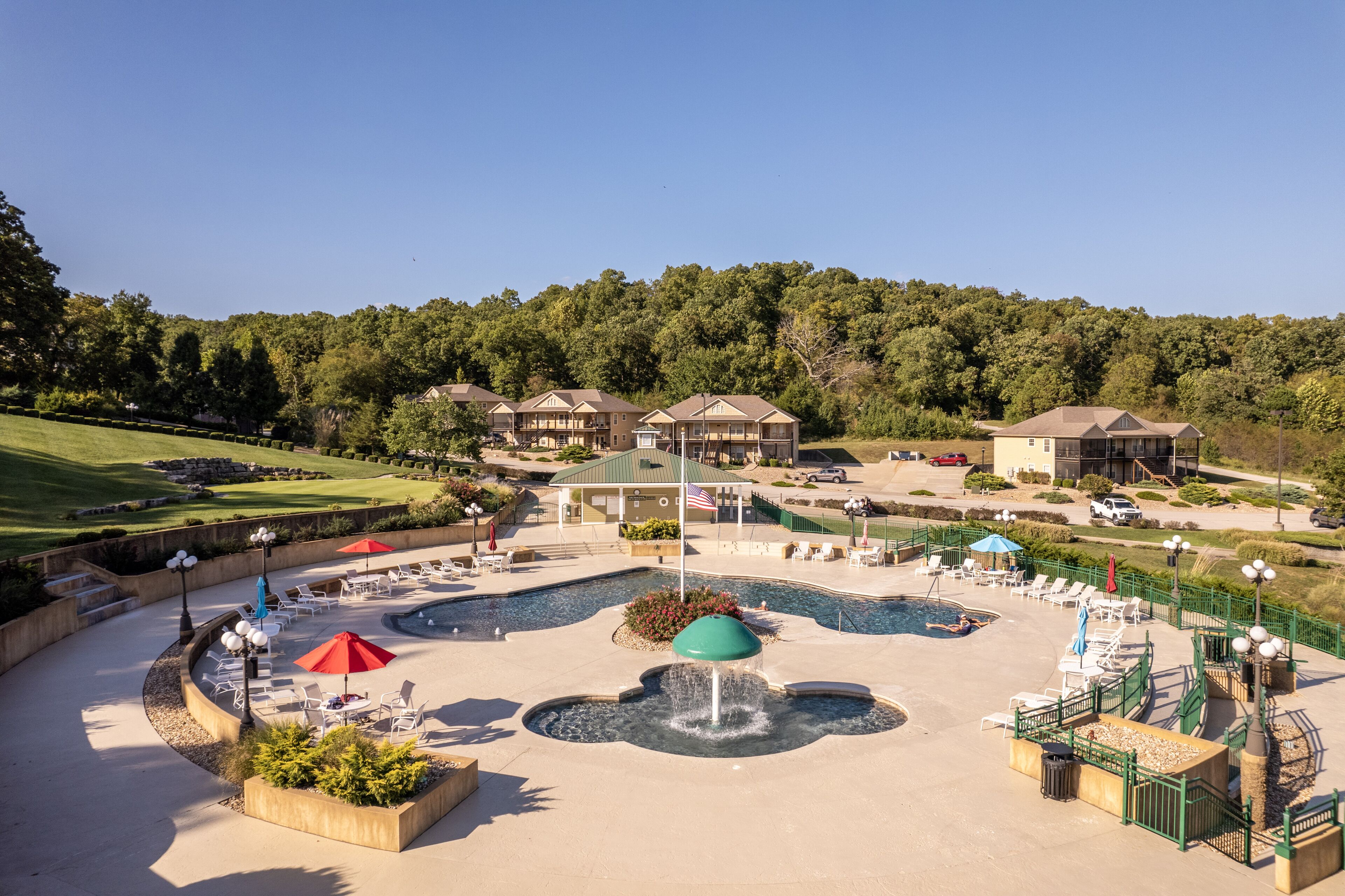 A resort with a central pool area, lounge chairs, and a fountain.