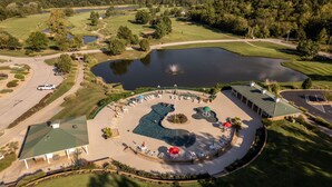 Vista aérea de un campo de golf con zona de natación, club house y aparcamiento.