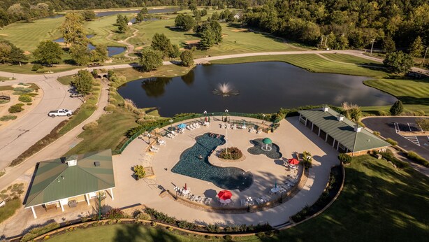 Vue aérienne d’un terrain de golf avec une zone de baignade, un club-house et un parking.
