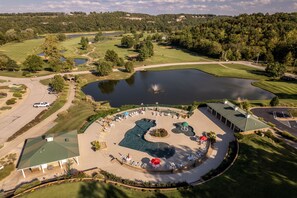 Vista aérea de un campo de golf con zona de natación, club house y aparcamiento.
