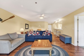 A living room with a sofa, coffee table, and a ceiling fan.