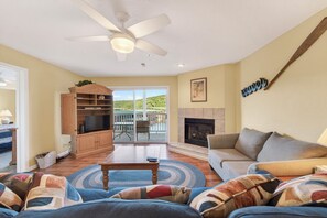 A living room with a sofa, a television, a fireplace, and a ceiling fan.