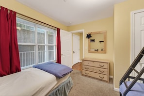A bedroom with a bed, a dresser, a mirror, and a staircase.