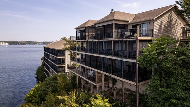 Un edificio de varios pisos frente al agua, con balcones, ventanas grandes y vistas al mar.