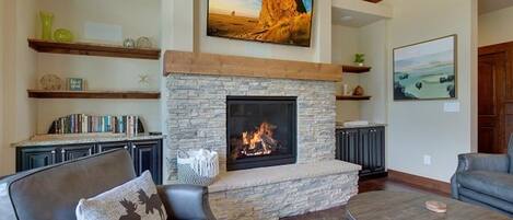 Una sala de estar con chimenea de piedra, sofás de cuero y una mesa de centro.