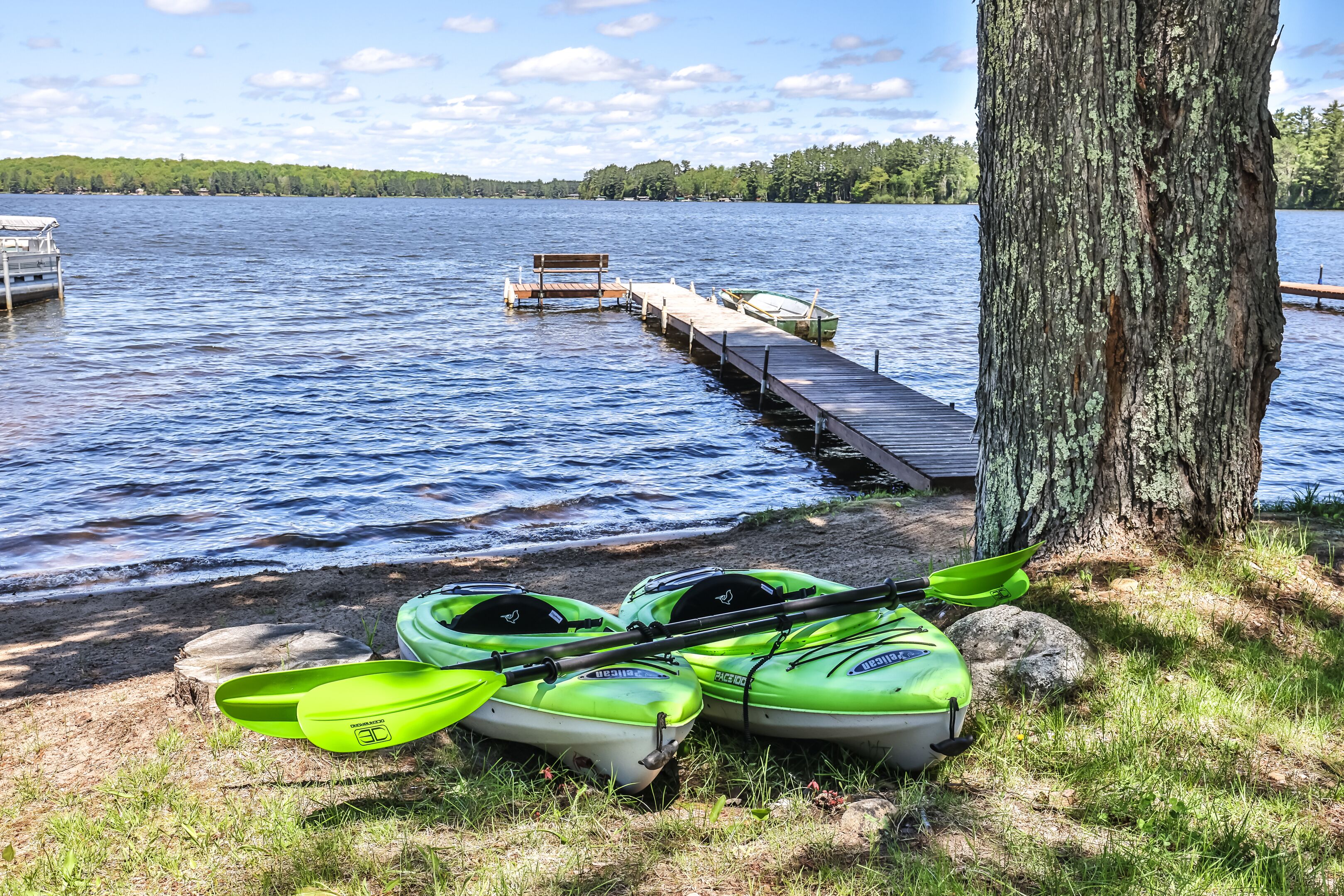 Un muelle que se adentra en un lago, con kayaks y un banco.