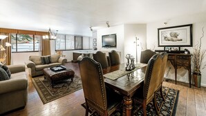 Un salón espacioso con una gran mesa de comedor, asientos cómodos y un televisor.