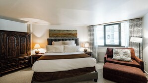 Un dormitorio con una cama grande, un armario de madera, un sofá pequeño y una ventana con cortinas.