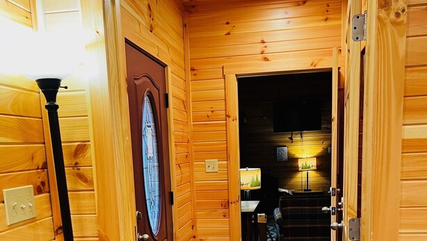 A wooden interior with a door, a bench, and a lamp.