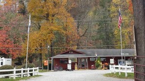 A small building with a red roof, a flag, and a signboard in front. - Ugly Cabin, Stunning Escape – Hot Tub! Fire Pit! Fast WIFI! Sunroom! Hiking! (Elkins)