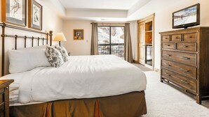 A bedroom with a large bed, a dresser, a television, and a window with a view of a snowy landscape. - Shadow Ridge 403 | Walk to Lifts | Mtn/Ski Views | Kitchen | Top Floor | Fireplace | Pool & Hot Tub (Park City)