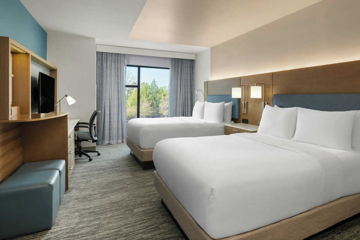 Une chambre d’hôtel avec deux lits, un bureau, une chaise et un téléviseur.