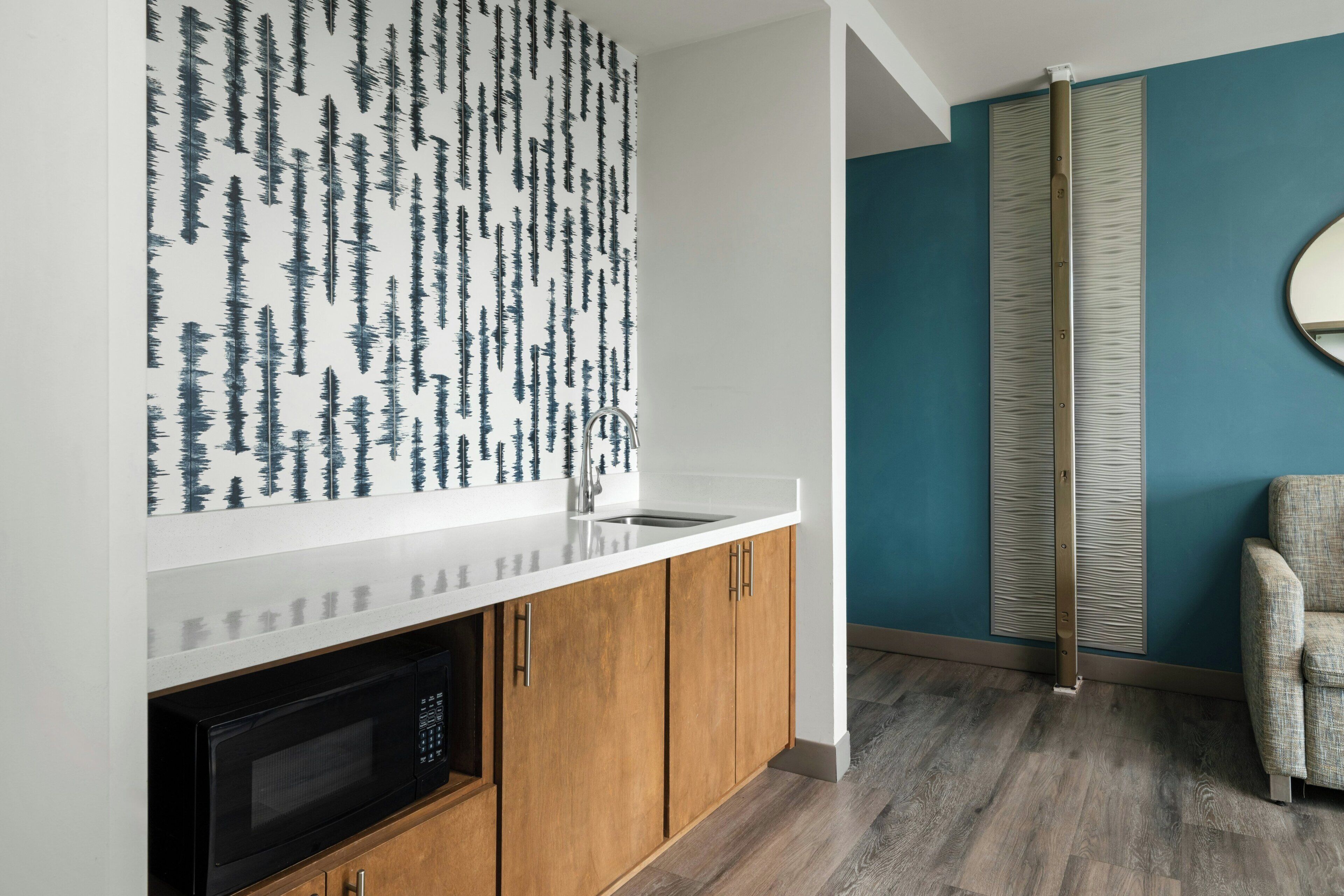 A kitchen with a white countertop, wooden cabinets, and a black microwave.