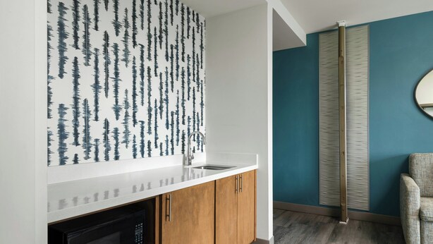A kitchen with a white countertop, wooden cabinets, and a black microwave. - EVEN Hotel Shenandoah - The Woodlands by IHG (Shenandoah)