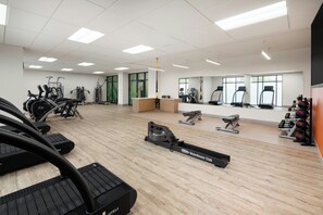 Un'ampia palestra con diverse macchine cardio, pesi liberi e un vogatore.