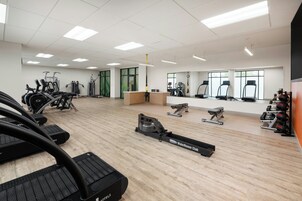 Un gimnasio amplio con diferentes máquinas de cardio, pesas y una máquina de remo.