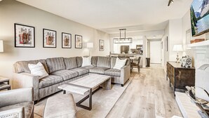 Un salon moderne avec un canapé d’angle, une table basse et une cheminée.