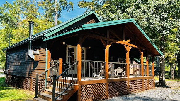 Eine Hütte mit Veranda, Holzstufen und Schornstein.