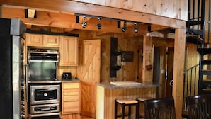 A kitchen with wooden cabinets, a stove, and a bar area with stools. - RIVERFRONT 2 STORY, 4 BR, 2 Bath, Washer/Dryer, HOT TUB, Pet Friendly (Elkins)