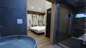 A modern bathroom with a large sink, a shower area, and a visible bedroom with a bed and curtains. - Chise Fukuro (Furano)