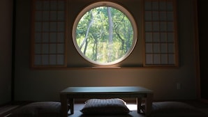 A room with a round window, a wooden bench, and two cushions. - Chise Fukuro (Furano)