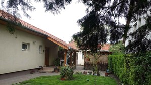 A courtyard with a small garden, a pergola, and a building with a tiled roof. - Holiday home with garden and terrace near the center (Siófok)