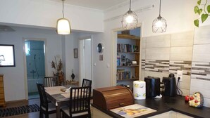 A modern kitchen with a wooden island, pendant lights, a bookshelf, and a visible shower area. - Holiday home with garden and terrace near the center (Siófok)