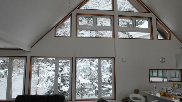 A room with large windows offering a view of snow-covered trees. - Furano Lodge 10 (Furano)
