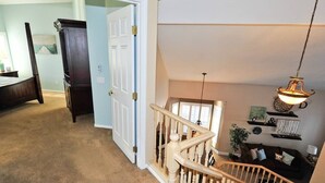 Un escalier menant à une chambre aménagée en mezzanine, avec vue sur l’extérieur.