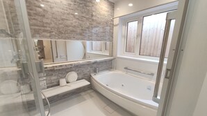 A modern bathroom with a large bathtub, a glass shower enclosure, and a vanity with a mirror.