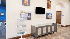 A hallway with a reception desk, a flat-screen TV, and artwork on the walls.