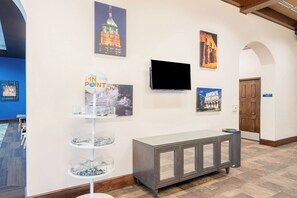 Un couloir avec un comptoir d’accueil, un téléviseur à écran plat et des œuvres d’art accrochées aux murs.