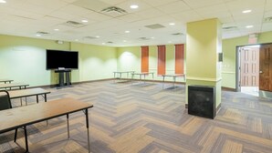 A conference room with a large flat-screen TV, multiple tables, and a herringbone-patterned floor.