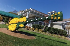 Stunning garden sculpture and classic home with a covered porch, set amidst mature landscaping.