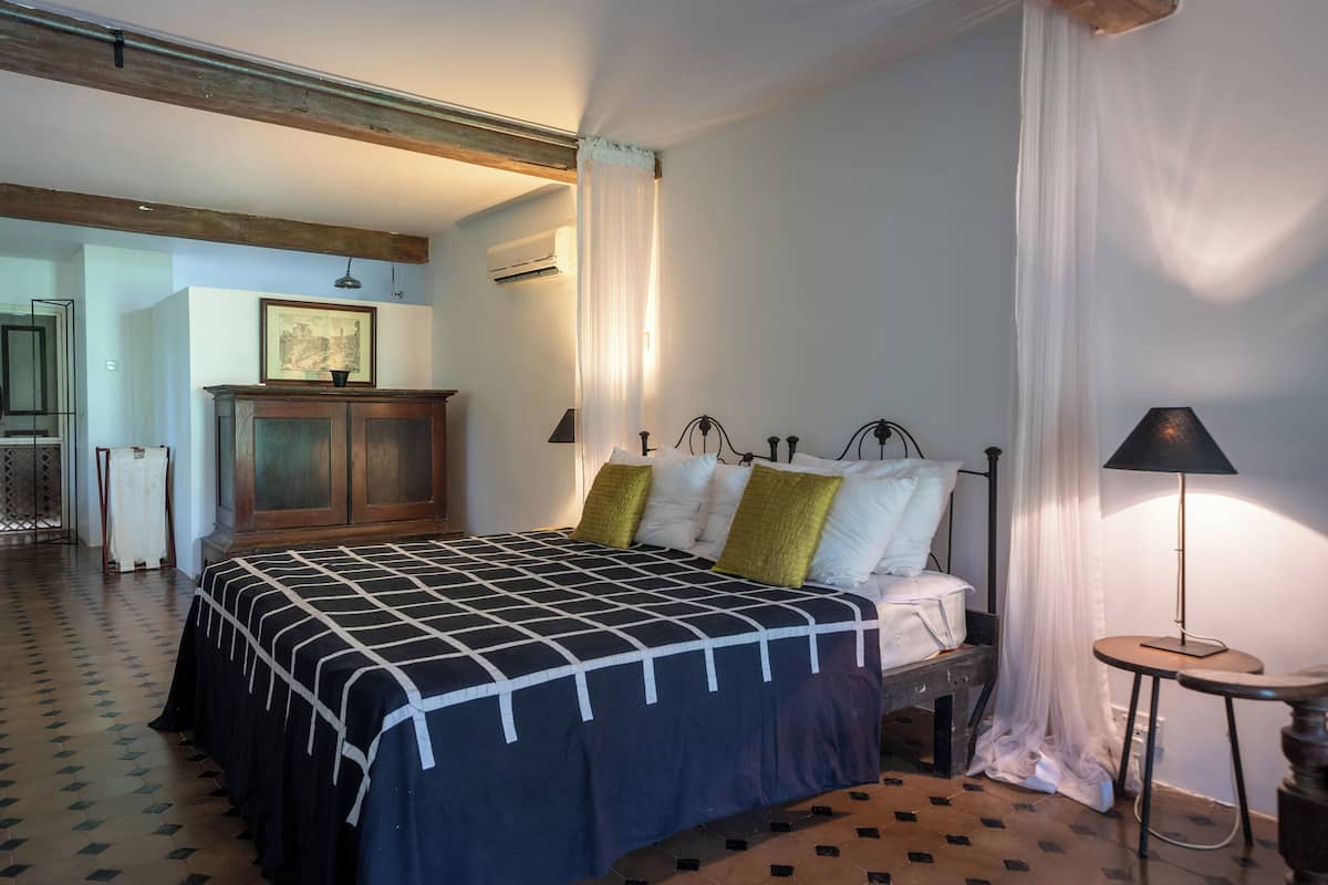 Een slaapkamer met een bed, nachtkastje, lamp en een kledingkast.