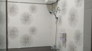 Baño con ducha, lavamanos e inodoro. Las paredes están revestidas con un diseño geométrico.