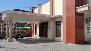 Un edificio con vestíbulo techado y una motocicleta estacionada afuera, con un letrero que indica un área comercial o de servicios.