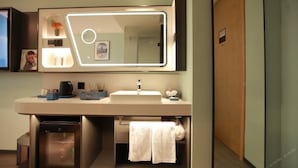 A modern bathroom with a large mirror, a sink, and a small cabinet. - Skybird Hotel Hongqiao Airport (Shanghai)
