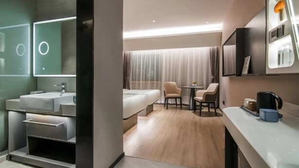 A modern hotel room with a large mirror, a bed, a small table, and a seating area. - Skybird Hotel Hongqiao Airport (Shanghai)