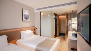 A hotel room with a bed, a bedside table, a mirror, and a door leading to a bathroom. - Skybird Hotel Hongqiao Airport (Shanghai)