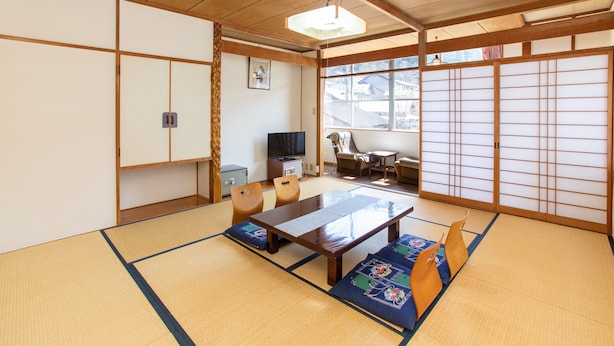Um quarto japonês tradicional com tatames, uma mesa de madeira baixa e portas deslizantes.